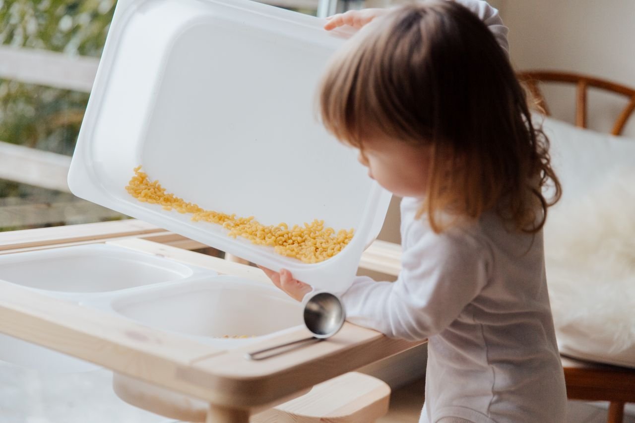 Mastering the First Impression: Your intriguing post title goes here Adorable child playing with pasta in a sensory tray, focusing on fun indoor learning.